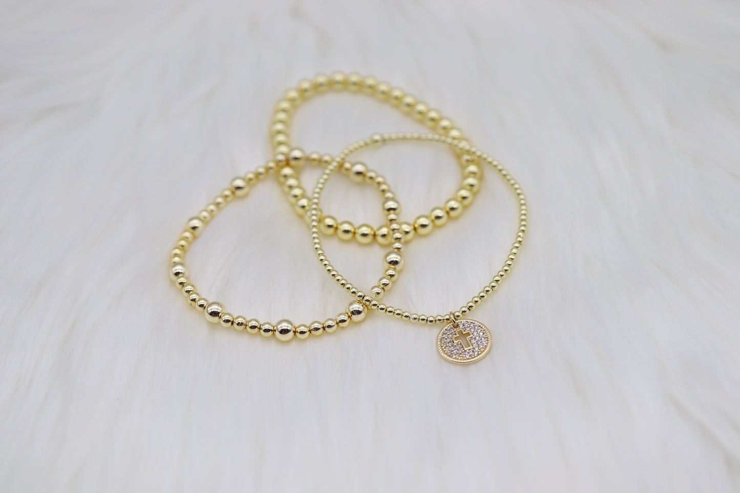 Triple Layered Gold Beaded Bracelet With Smaller Cross Dangling Pendant