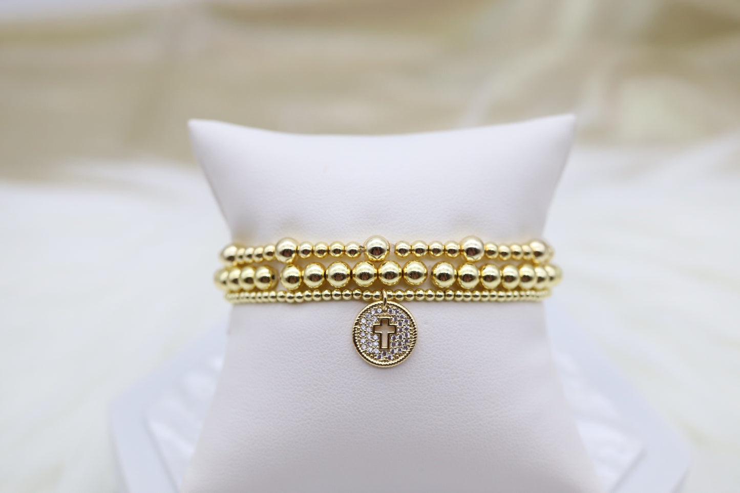 Triple Layered Gold Beaded Bracelet With Smaller Cross Dangling Pendant