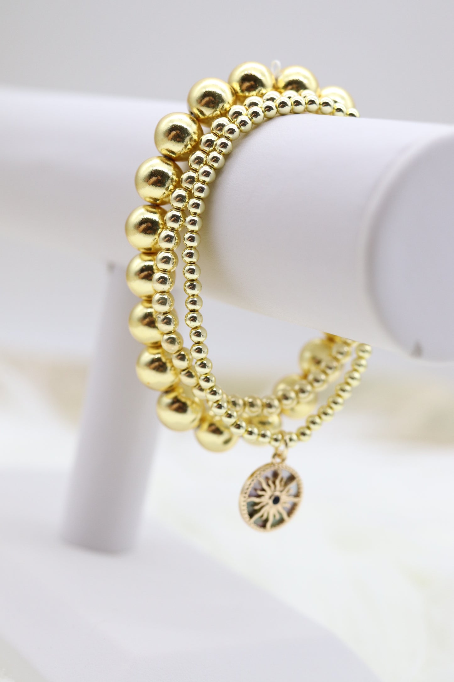 Triple Layered Gold Beaded Elastic Bracelet With Starburst Dangling Pendant