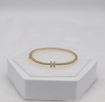 Gold-Tone Hinged Bangle with Crystal Accents and “H” Centerpiece