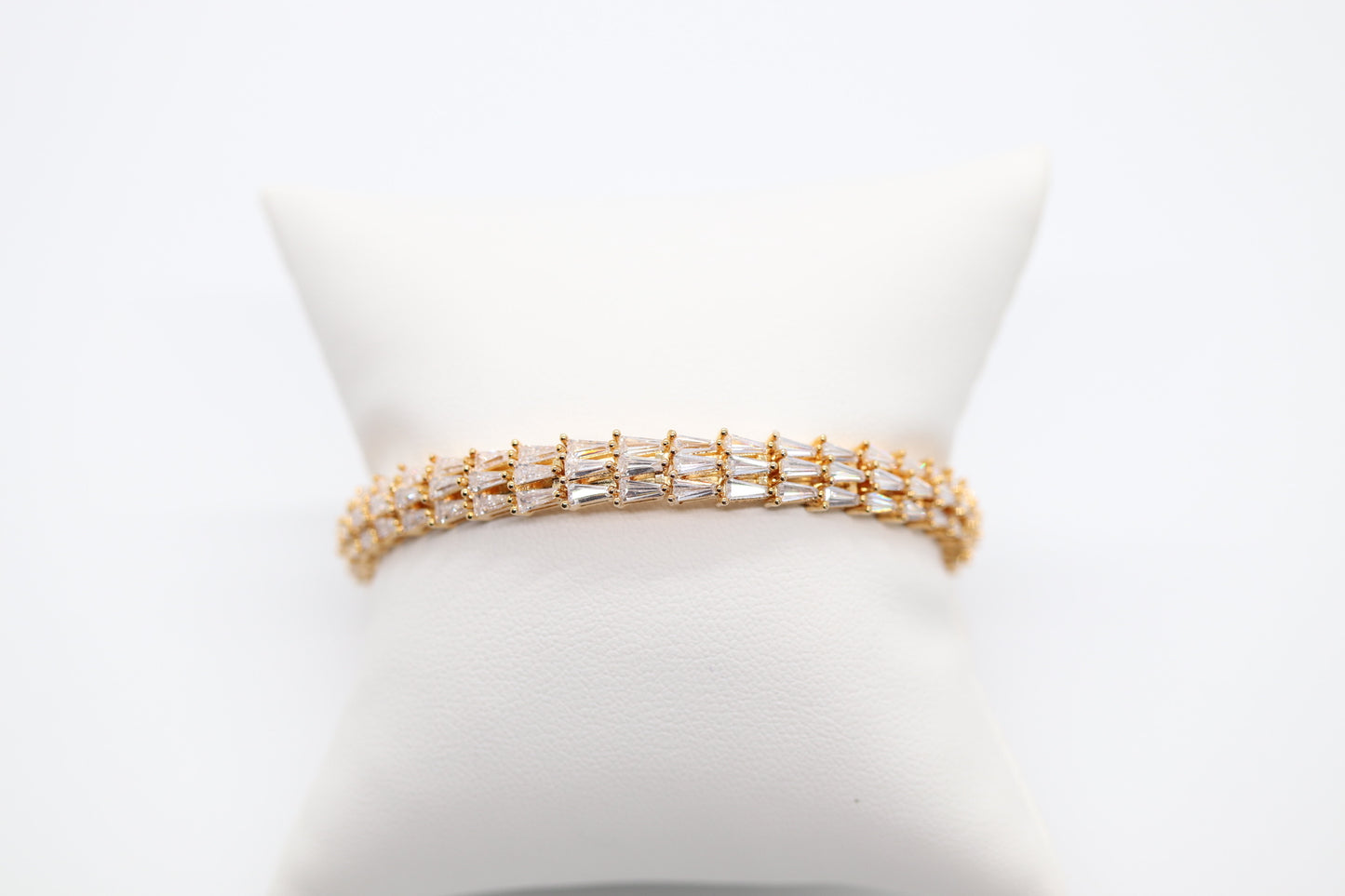 Triple Row Gold bracelet with tapered baqueets and has hinge.